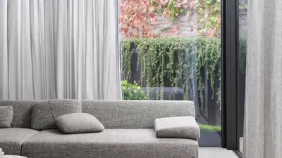 Sheer curtains behind a sofa with a leafy garden view