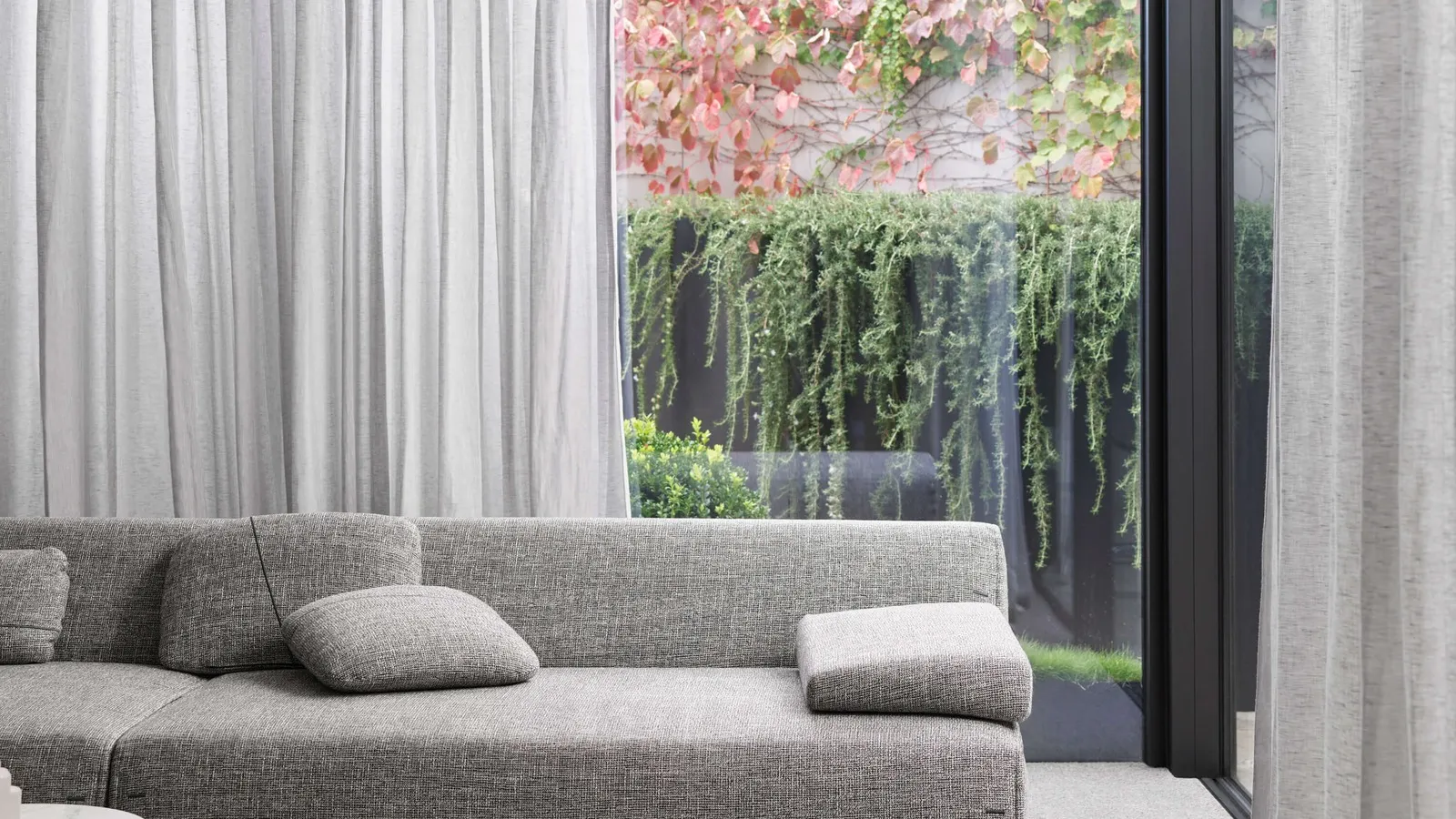 Sheer curtains behind a sofa with a leafy garden view